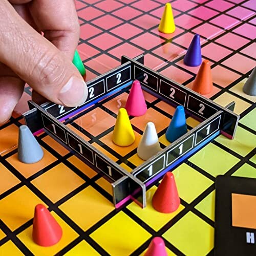 A hand arranging colorful cone-shaped pieces on a board game.