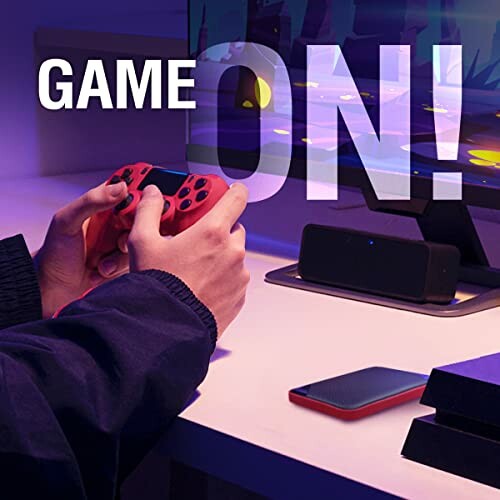 Person holding a gaming controller in front of a screen with 'Game On!' text.